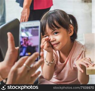 Little asian girl take a photo with a smartphone.