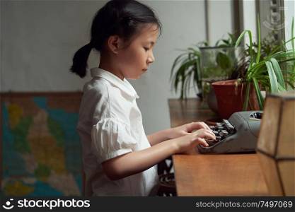 Little asian girl using old vintage typewriter to studying