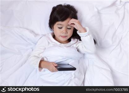 Little asian girl using smartphone and lying on the bed . child addicted phone.