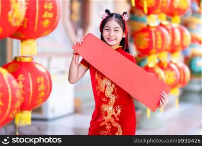 little Asian girl wearing red traditional Chinese cheongsam decoration show blank paper red and lanterns with the Chinese text Blessings written on it Is a Fortune blessing for Chinese New Year