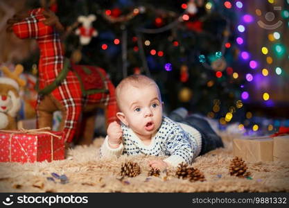 little baby boy lying on his stomach in the room with Christmas decorations