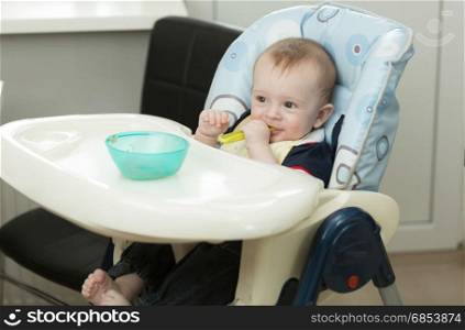 Little baby boy playing with food and dish while eating