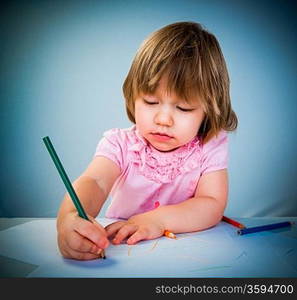 Little baby girl draws pencil on a blue background