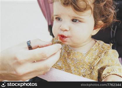 Little baby girl eating a strawberry