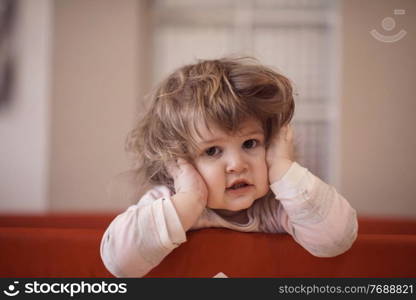 little baby girl with strange hairstyle and curlers in bed at home