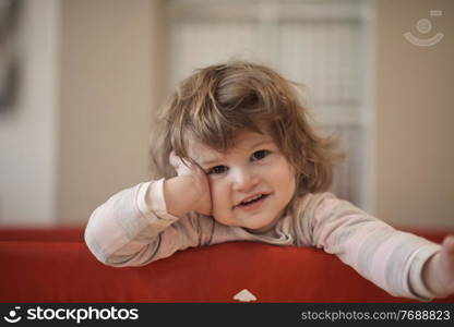 little baby girl with strange hairstyle and curlers in bed at home