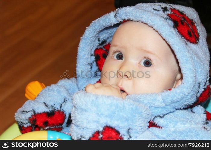 little baby in blue dressing gown with amazed sight