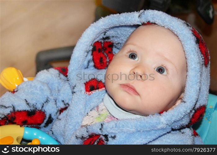 little baby in blue dressing gown with amazed sight. little lovely baby lying on the bed