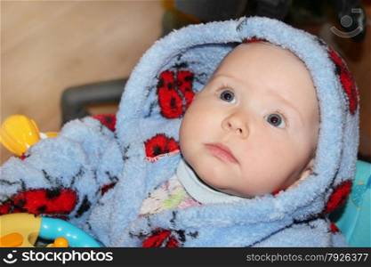 little baby in blue dressing gown with amazed sight. little lovely baby lying on the bed