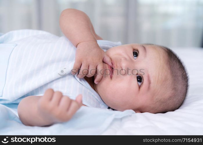 little baby with finger in mouth on a bed