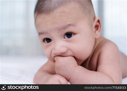little baby with finger in mouth on a bed