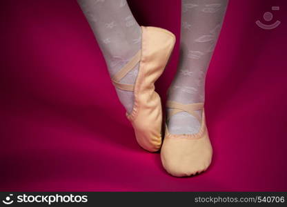 little ballerina's legs in pointe on a pink background. ballet position