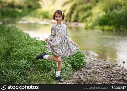 Little beautiful girl in nature stream wearing beautiful dress