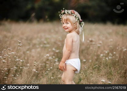 little beautiful girl on nature on summer day vacation. childgirl in panties and a flowers wreath on her head is playing in the field on summer day. The concept of family holiday and time together.. little beautiful girl on nature on summer day vacation. childgirl in panties and a flowers wreath on her head is playing in the field on summer day. The concept of family holiday and time together