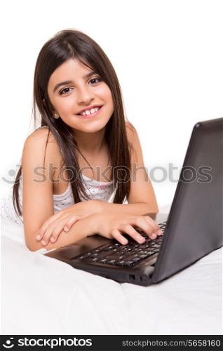 Little beautiful girl with a laptop on bed