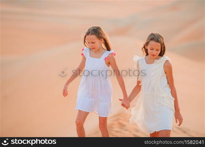 Little beautiful girls at dunes in most big sand desert in the world. Girls among dunes in Rub al-Khali desert in United Arab Emirates
