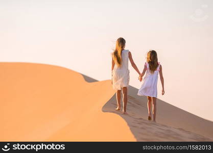 Little beautiful girls at dunes in most big sand desert in the world at sunset. Girls among dunes in Rub al-Khali desert in United Arab Emirates