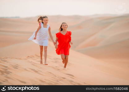 Little beautiful girls at dunes in most big sand desert in the world at sunset. Girls among dunes in Rub al-Khali desert in United Arab Emirates