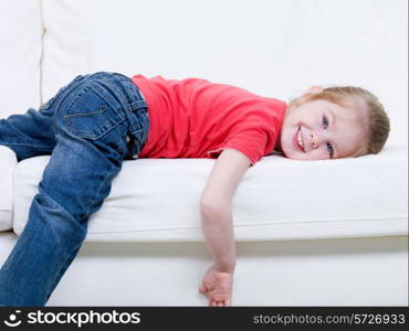 Little beautiful smiling girl in casuals frolic on the sofa - indoors