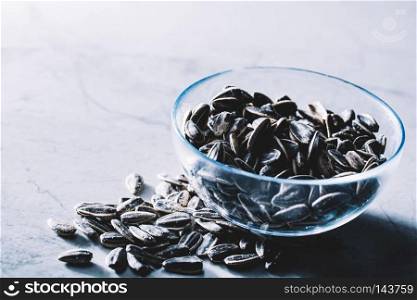 Little black sunflower seeds in a glass bowl. Healthy snacks. Fit lifestyle and diet.. Little black sunflower seeds in a glass bowl.