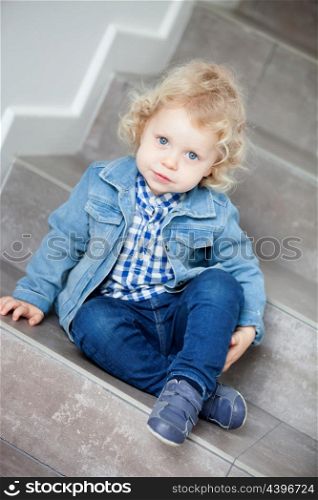 Little blond baby sitting on the stairs at home