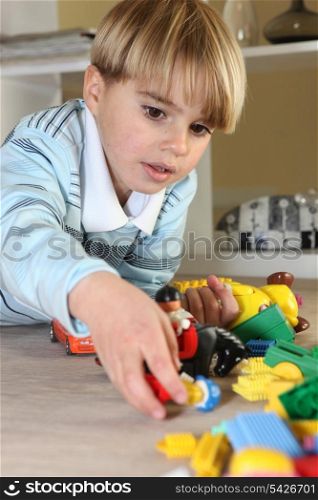 Little blond boy playing with toys