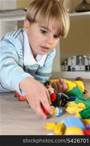 Little blond boy playing with toys