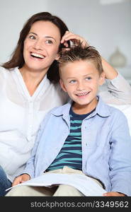 Little blond boy sitting on sofa with his mother