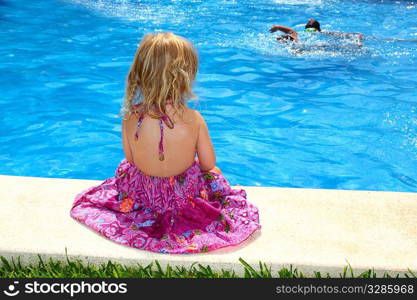 Little blond girl sitting rear back swimming pool outdoor