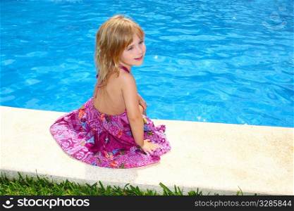 Little blond girl sitting smiling swimming pool outdoor