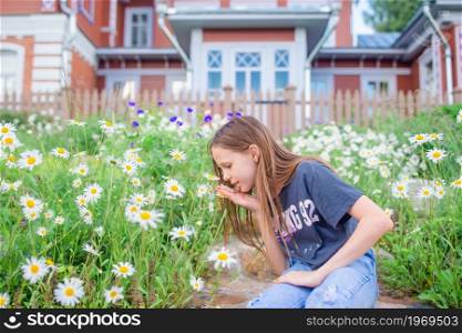 Little blonde caucasian girl pick flowers in her yard. Little blonde girl pick flowers in a meadow full of chamomiles