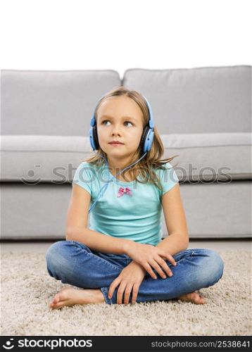 Little blonde girl at home listen music with headphones