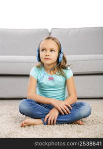 Little blonde girl at home listen music with headphones