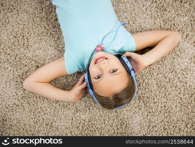 Little blonde girl at home listen music with headphones