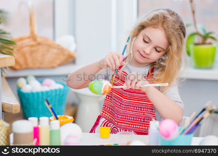 Little blonde girl coloring eggs for Easter holiday at home. Little blonde girl coloring eggs for Easter holiday at home.