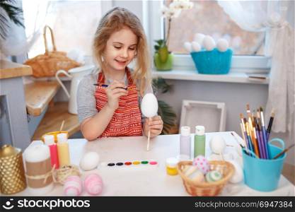 Little blonde girl coloring eggs for Easter holiday at home. Little blonde girl coloring eggs for Easter holiday at home.