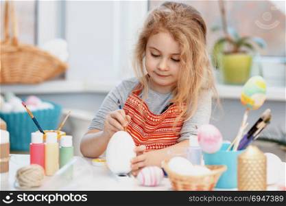 Little blonde girl coloring eggs for Easter holiday at home. Little blonde girl coloring eggs for Easter holiday at home.