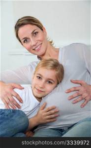 Little blonde girl listening to pregnant woman belly