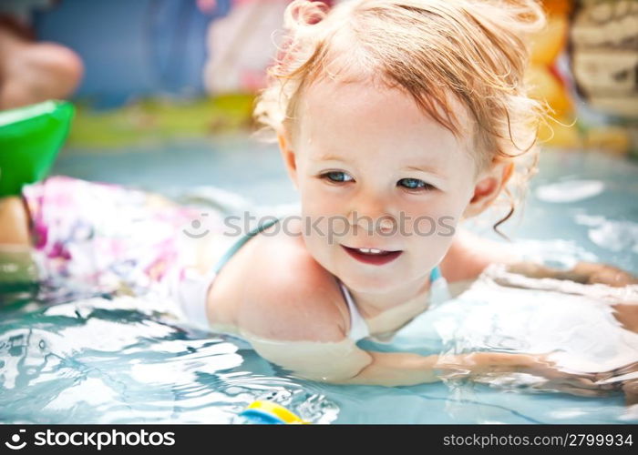 Little blondie girl in the swimming pool, soft focus