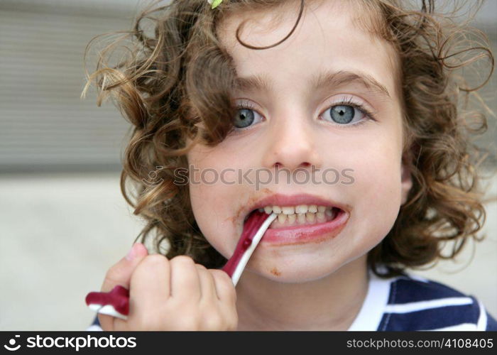 Little blue eyes girl eating sweet candy with dirty face