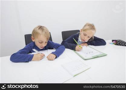 Little boy and daughter writing on documents at table