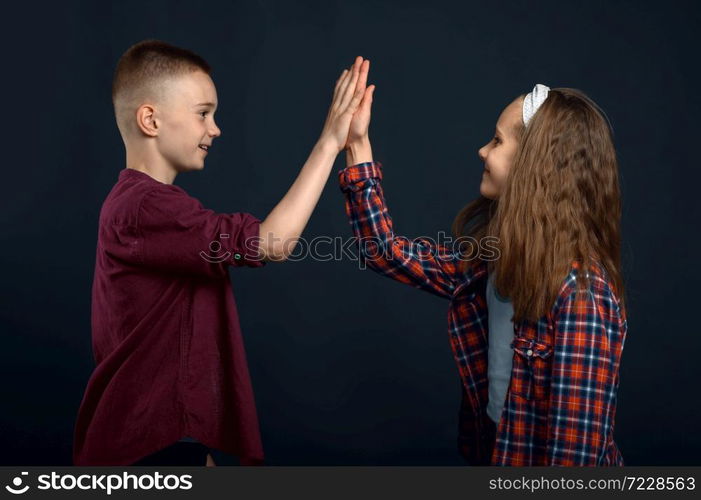 Little boy and girl beats the palms in studio. Happy childhood, children having fun, funny kids isolated on dark background, child emotion. Little boy and girl beats the palms in studio