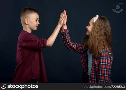Little boy and girl beats the palms in studio. Happy childhood, children having fun, funny kids isolated on dark background, child emotion. Little boy and girl beats the palms in studio