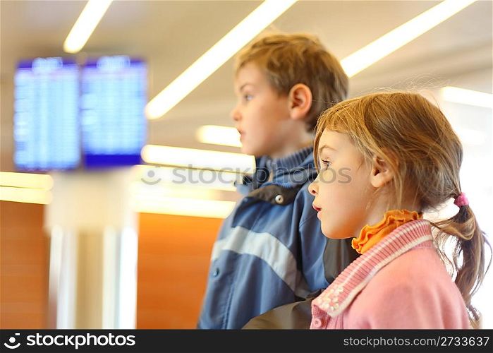little boy and girl in airport blue screens on background side view half body