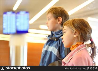 little boy and girl in airport blue screens on background side view half body
