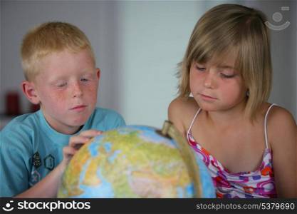 little boy and girl looking at a globe