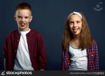 Little boy and girl making faces in studio. Happy childhood, children having fun, funny kids isolated on dark background, child emotion. Little boy and girl making faces in studio