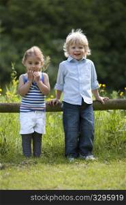 Little Boy And Girl standing Together In The Parc Looking Into The Camera