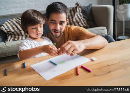 Little boy and his father spending time together drawing at home.