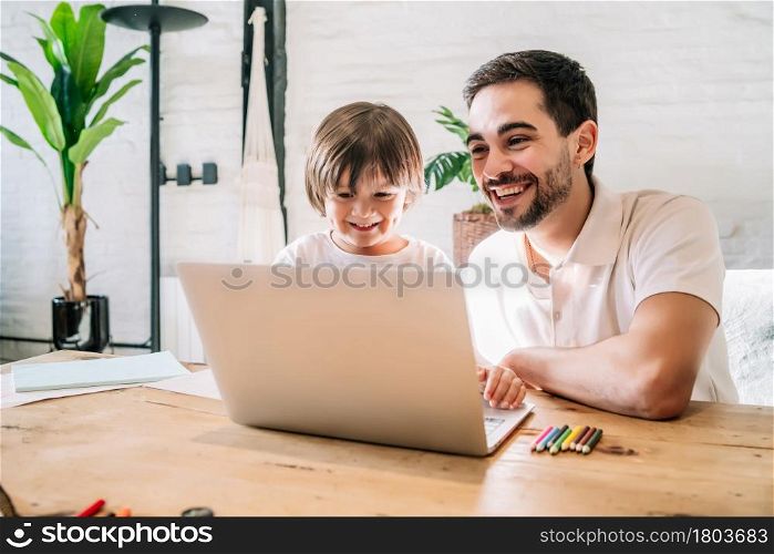 Little boy and his father using a laptop together while staying at home. New normal lifestyle. Monoparental concept.